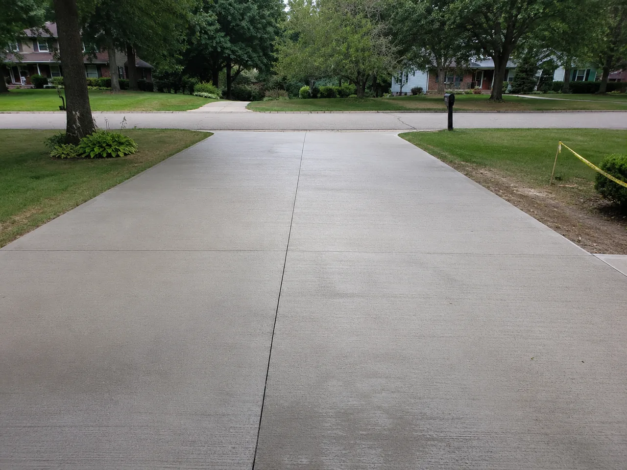 Broom-finish concrete driveway lined with trees in Livonia, MI