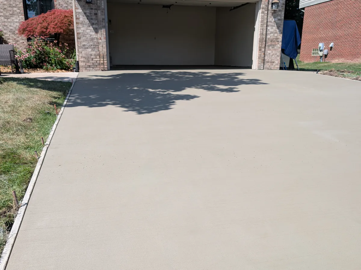 Wide broom-finish concrete driveway running to an attached garage in Livonia, MI