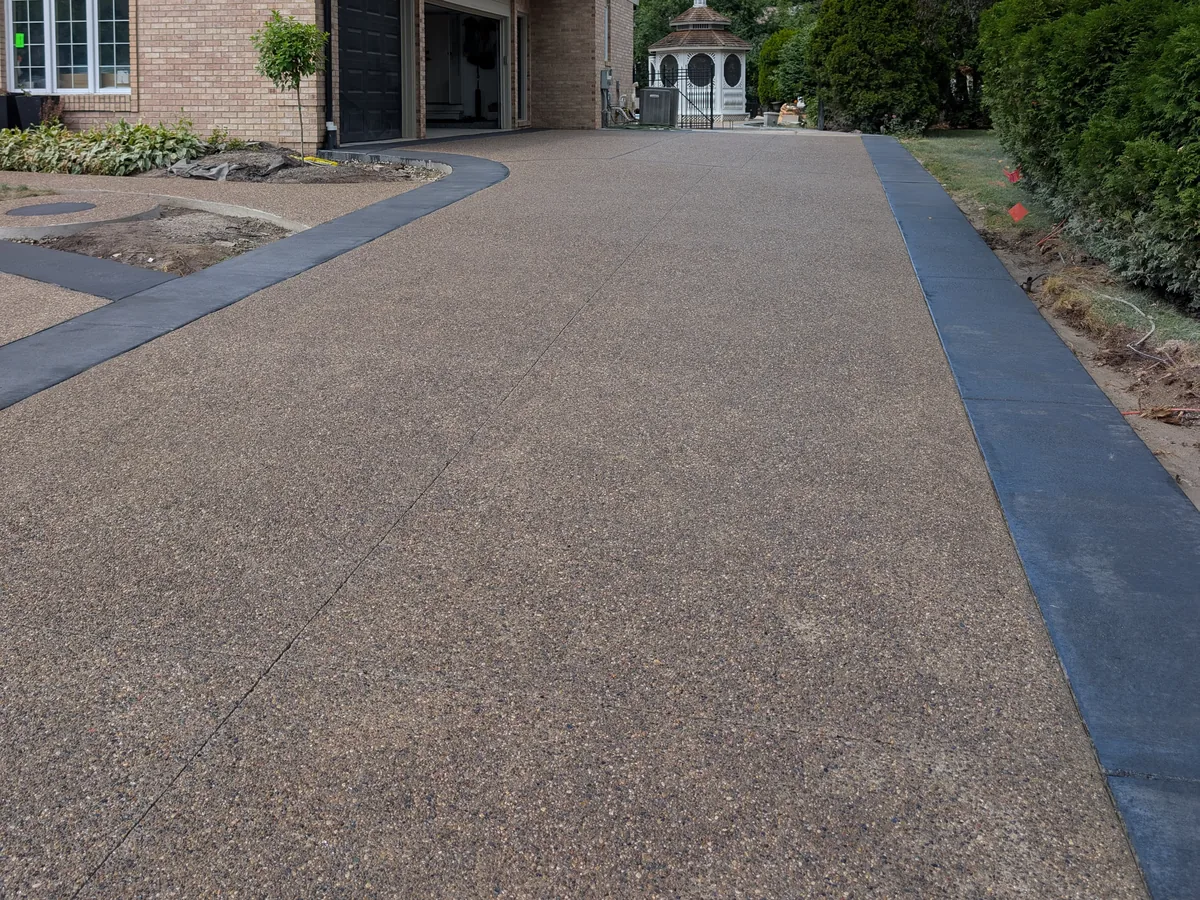 Finished exposed aggregate driveway with charcoal border, same view as the base photo, Troy MI