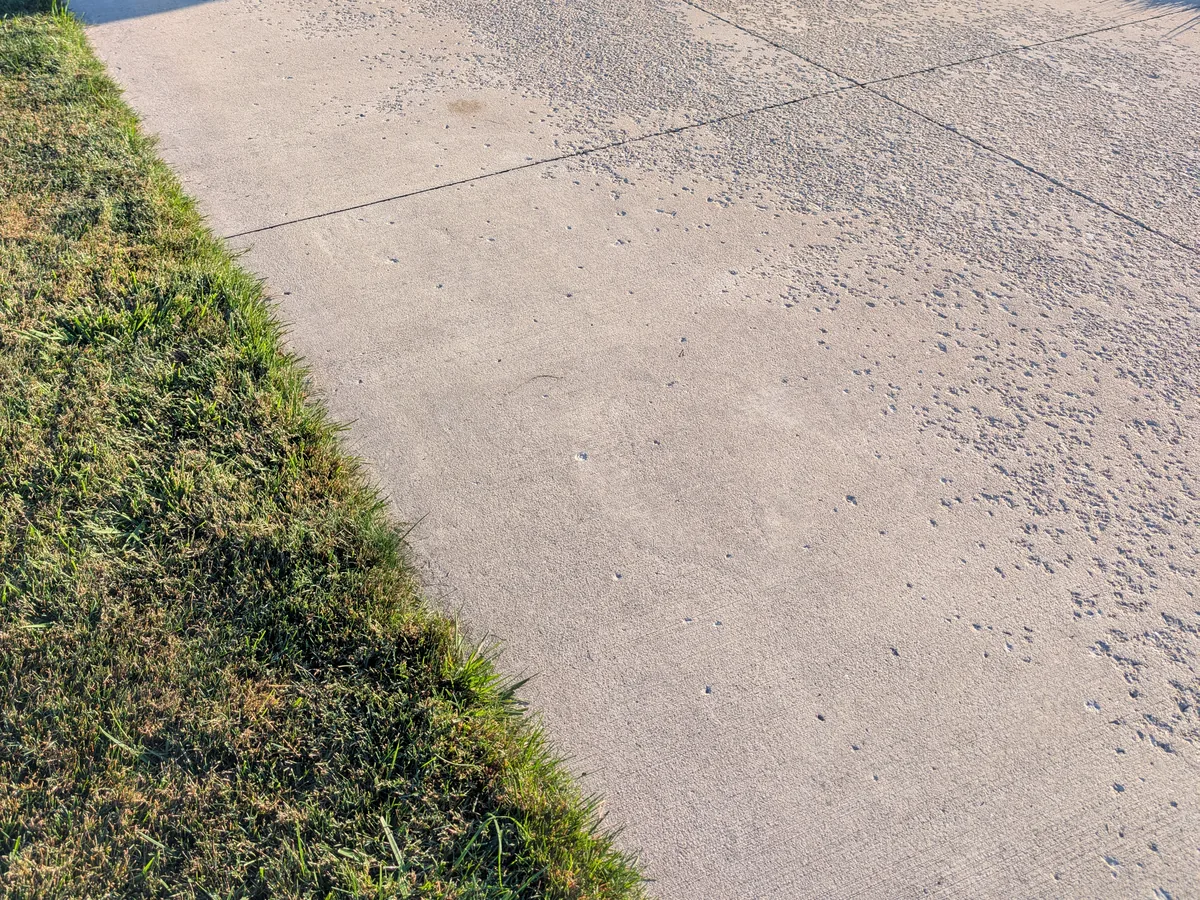 Concrete driveway with surface scaling, aggregate exposed and popping out, worst near the street where road salt collects, Dearborn Heights MI